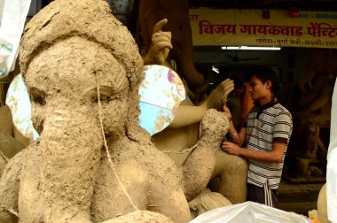 Nagpur, Maharashtra - 3 Ağustos 2014: Sanatçı 3 Ağustos 2014 'te Hindistan' ın Maharashtra kentinde Ganesha-Festivali için bir sanatçı atölyesinde Hindu tanrısı Lord Ganesha 'nın bir putuna son rötuşlarını yaptı..