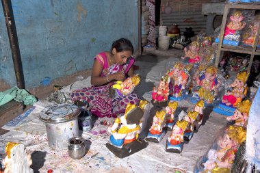 AMRAVATI, MAHARASHTRA - SEPTEMBER 4, 2016: Artist making a statue and gives finishing touches on an idol of the Hindu god Lord Ganesha at an artist's workshop for Ganesha festival.