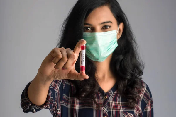 Woman holding a test tube with blood sample for coronavirus or 2019-nCoV analyzing.