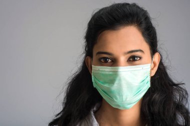 Tıbbi ya da cerrahi maske takan genç bir kız ya da kadın doktorun yakın plan portresi
