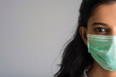 Tıbbi ya da cerrahi maske takan genç bir kız ya da kadın doktorun yakın plan portresi