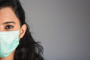 Tıbbi ya da cerrahi maske takan genç bir kız ya da kadın doktorun yakın plan portresi