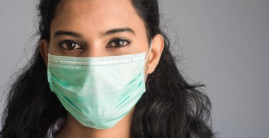 Tıbbi ya da cerrahi maske takan genç bir kız ya da kadın doktorun yakın plan portresi