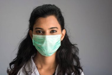 Tıbbi ya da cerrahi maske takan genç bir kız ya da kadın doktorun yakın plan portresi