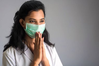 Genç kadın doktor COVID-19 salgını yüzünden Namaste yapıyor. Sarılma veya tokalaşma yerine koronavirüsün yayılmasını önlemek için yeni bir selamlama.