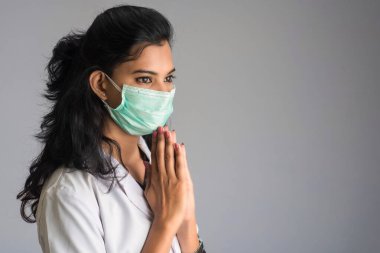 Genç kadın doktor COVID-19 salgını yüzünden Namaste yapıyor. Sarılma veya tokalaşma yerine koronavirüsün yayılmasını önlemek için yeni bir selamlama.