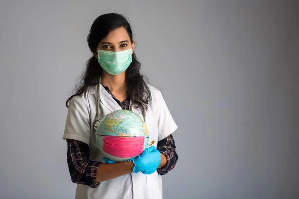 Woman doctor holding world globe with a medicine face mask. World epidemic of coronavirus concept.