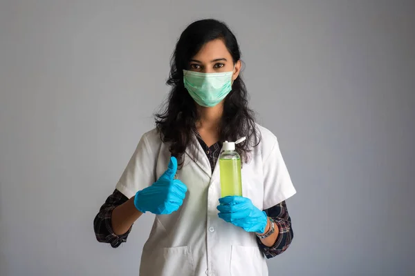 Kadın doktorun portresi el temizliği için bir şişe dezenfekte jeli gösteriyor..