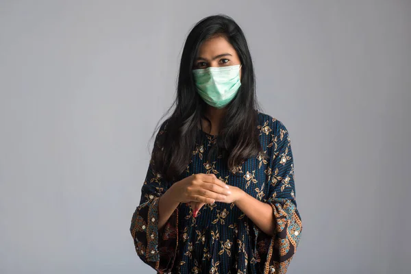 Genç bir kızın portresi, el temizliği için şişedeki dezenfekte edici jeli kullanıyor veya gösteriyor..