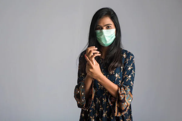 Genç bir kızın portresi, el temizliği için şişedeki dezenfekte edici jeli kullanıyor veya gösteriyor..