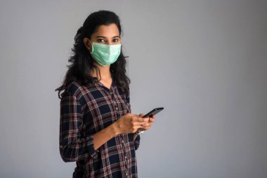 Cerrahi maskeli bir kadın iletişim için akıllı telefon kullanıyor. ev kavramından çalışma.