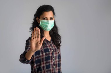 Tıbbi maskeli bir kadın portresi dur işaretini elleriyle gösteriyor. Sağlık ve Tıp Konsepti