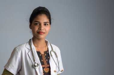 Gri arka planda steteskobu olan kadın doktor.