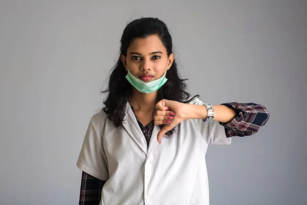 Young woman doctor wearing medical face mask Showing sign. Doctor woman wearing surgical mask for corona virus.