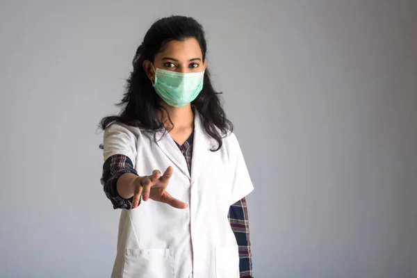 Young woman doctor wearing medical face mask Showing sign. Doctor woman wearing surgical mask for corona virus.