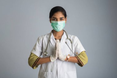 Genç kadın doktor COVID-19 salgını yüzünden Namaste yapıyor. Sarılma veya tokalaşma yerine koronavirüsün yayılmasını önlemek için yeni bir selamlama.