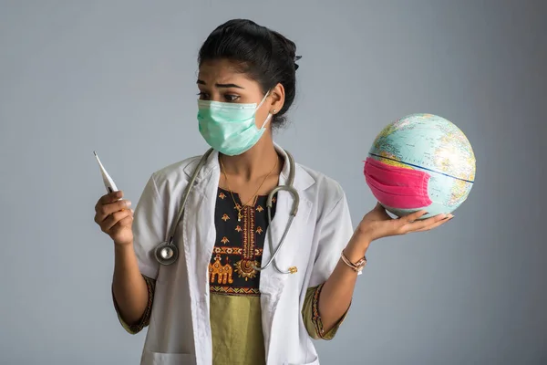 woman doctor holding Earth globe for presenting virus pandemic outbreak on the whole planet. Global warming and temperature rising presentation.