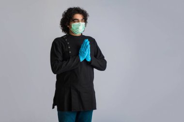 Genç adam COVID-19 salgını yüzünden Namaste 'ı yapıyor. Sarılma veya tokalaşma yerine koronavirüsün yayılmasını önlemek için yeni bir selamlama. Zihinsel denge için yoga pratiği.