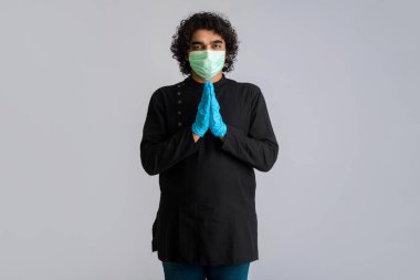 Genç adam COVID-19 salgını yüzünden Namaste 'ı yapıyor. Sarılma veya tokalaşma yerine koronavirüsün yayılmasını önlemek için yeni bir selamlama. Zihinsel denge için yoga pratiği.