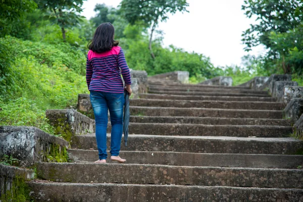 A beautiful young woman walking on the stairs outdoors or park or in the forest.