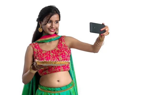아름다운 소녀가 배경에 스마트폰을 사용하여 가벼운 기간에 램프나 디야를 셀피를 — 스톡 사진