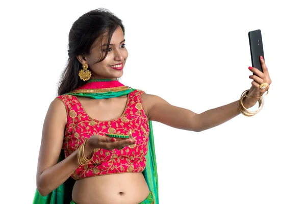 美しい若いです幸せな女の子は白い背景にスマートフォンを使用して光Diwaliの祭りの間に粘土ランプやDiyaで自撮り — ストック写真
