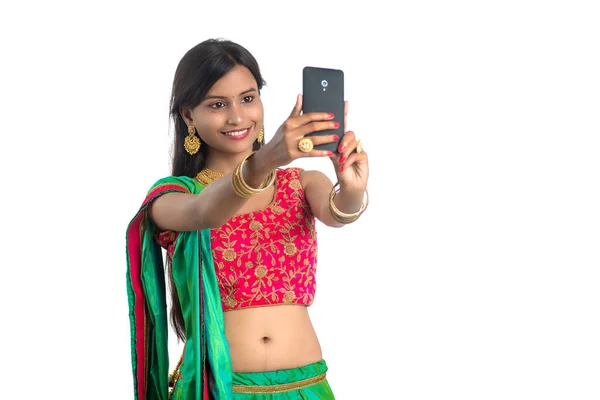 携帯電話やスマートフォンを使用して若いインド人の女の子 セルフィーを話すか 白い背景に隔離されたビデオチャットで話して — ストック写真