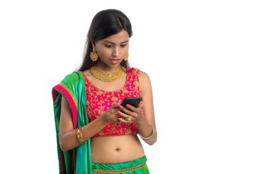 Genç Hintli geleneksel kız beyaz arka planda izole edilmiş cep telefonu ya da akıllı telefon kullanıyor.