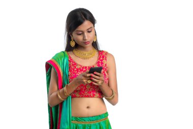 Genç Hintli geleneksel kız beyaz arka planda izole edilmiş cep telefonu ya da akıllı telefon kullanıyor.