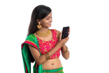 Genç Hintli geleneksel kız beyaz arka planda izole edilmiş cep telefonu ya da akıllı telefon kullanıyor.