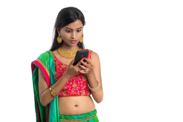 白い背景に隔離された携帯電話やスマートフォンを使用して若いインドの伝統的な女の子 — ストック写真