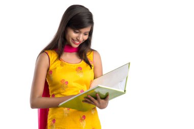 Elinde kitapla beyaz arka planda poz veren güzel bir genç kız.