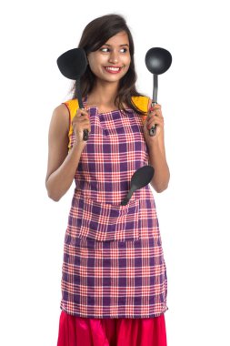 Genç Hintli kadın mutfak aletlerini tutuyor (kaşık, stapula, kepçe, ve tava, vb.) beyaz arkaplanda