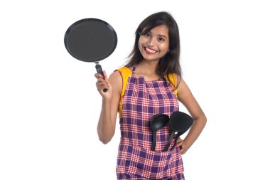 Genç Hintli kadın mutfak aletlerini tutuyor (kaşık, stapula, kepçe, ve tava, vb.) beyaz arkaplanda