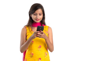 Beyaz arka planda izole edilmiş cep telefonu ya da akıllı telefon kullanan genç bir Hintli kız.