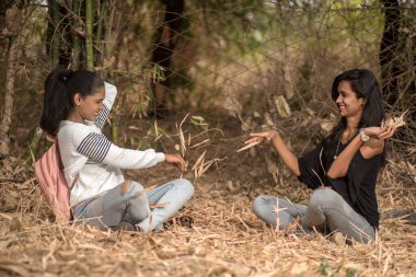 Parkta düşen yapraklarla oynayan mutlu kızlar