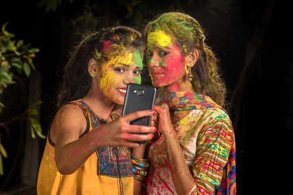 幸せな若い女の子のグループは ホリ祭りにスマートフォンを使用して楽しさと自撮りを持っています 祭りと技術の概念 — ストック写真