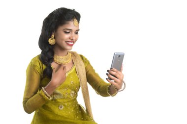 Genç Hintli geleneksel kız beyaz arka planda izole edilmiş cep telefonu ya da akıllı telefon kullanıyor.