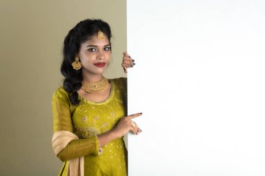 Geleneksel Kız boş beyaz tabela tutuyor ve gösteriyor