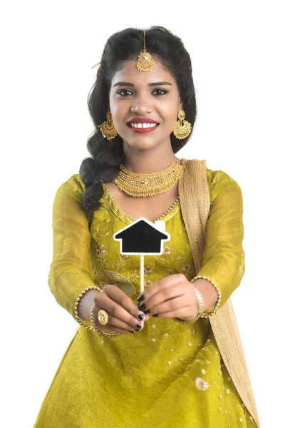 幸せなインドの伝統的な若いです女性保持A小さな家カットアウトボードで彼女の手で白い背景 — ストック写真