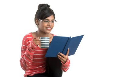 Beyaz bir arka planda duran kitap ve kahveyle güzel bir genç kız..