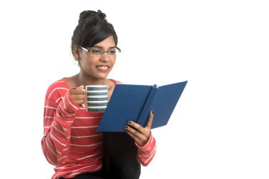 Beyaz bir arka planda duran kitap ve kahveyle güzel bir genç kız..