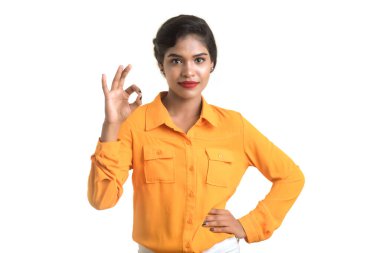 Gülümseyen neşeli kız beyaz arka planda izole edilmiş işaret gösteriyor.