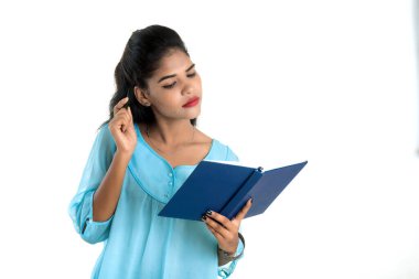 Elinde kitapla beyaz arka planda poz veren güzel bir genç kız.