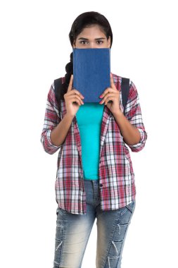 Sırt çantalı genç Hintli kadın ayakta duruyor ve elinde defterlerle beyaz bir arka planda poz veriyor..