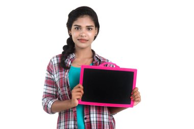 Beyaz bir arka planda tahtayla poz veren güzel bir genç kız.