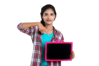 Beyaz bir arka planda tahtayla poz veren güzel bir genç kız.