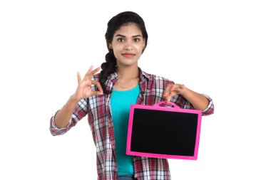 Beyaz bir arka planda tahtayla poz veren güzel bir genç kız.