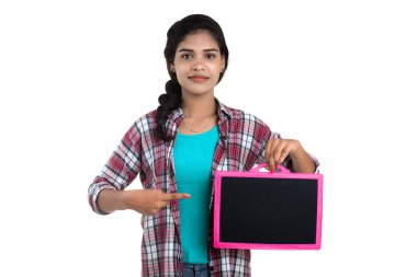 Beyaz bir arka planda tahtayla poz veren güzel bir genç kız.