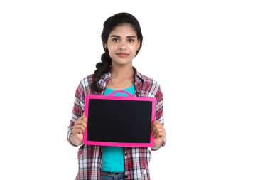 Beyaz bir arka planda tahtayla poz veren güzel bir genç kız.